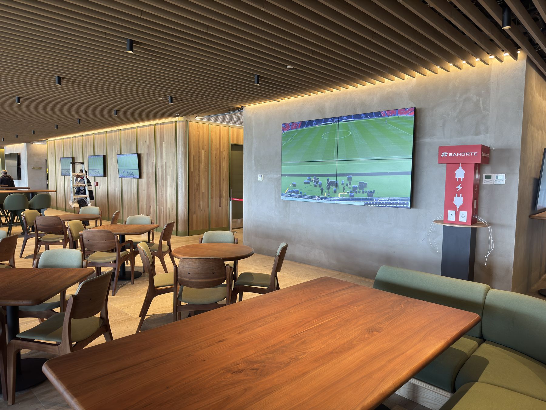 Lounge del estadio con pantalla de gran formato transmitiendo el partido